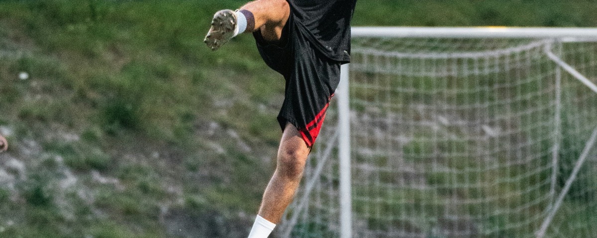 A young footballer practises close control on a training field.
