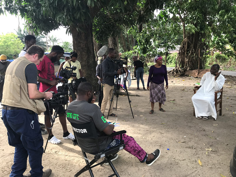 A film crew records a scene outdoors in Nigeria.