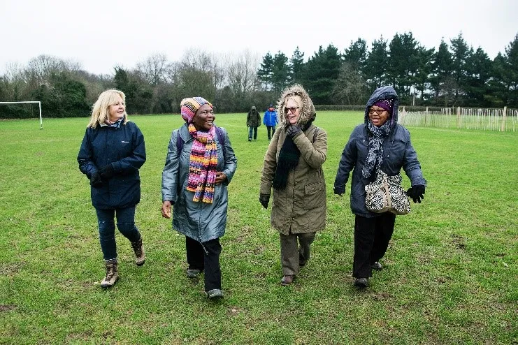 Four adults walk together across a grassy area during a community health walk.